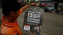 Seorang warga membaca poster yang dibagikan oleh KPU saat sosialisasi Pilkada DKI 2017 di Terminal Senen, Jakarta, Minggu (18/12). Sosialisasi pesta demokrasi ini guna mencegah banyaknya pemilih yang golongan putih atau golput. (Liputan6.com/Johan Tallo)