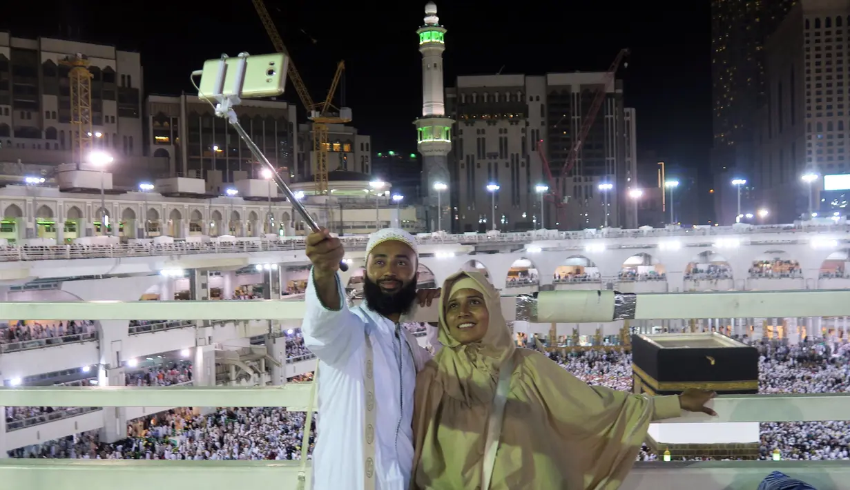 Dua umat Muslim berfoto dengan latar belakang Kabah saat melaksanakan ibadah haji di Masjidil Haram, Mekah, Minggu (4/9). Kepadatan semakin terlihat jelas di Masjidil Haram jelang pelaksanaan Haji 2016. (REUTERS/Ahmed Jadallah)