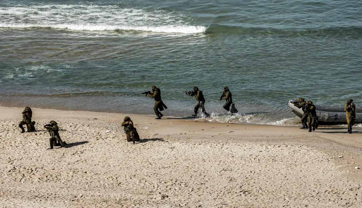 Pejuang bersenjata turun dari perahu karet di pantai selama latihan militer di Kota Gaza (29/12/2020).  Untuk pertama kalinya, Hamas bersama sayap militer kelompok-kelompok perlawanan Palestina lainnya menggelar latihan perang gabungan. (AFP/Mohammed Abed)