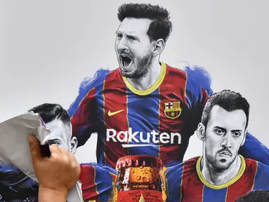 Pekerja melepas poster yang menampilkan pemain depan Argentina, Lionel Messi di pintu masuk Stadion Camp Nou, Barcelona pada Selasa, 10 Agustus 2021. Lionel Messi resmi meninggalkan Barcelona akibat masalah finansial klub dan peraturan dari Liga Spanyol. (AFP/Pau Barrena)