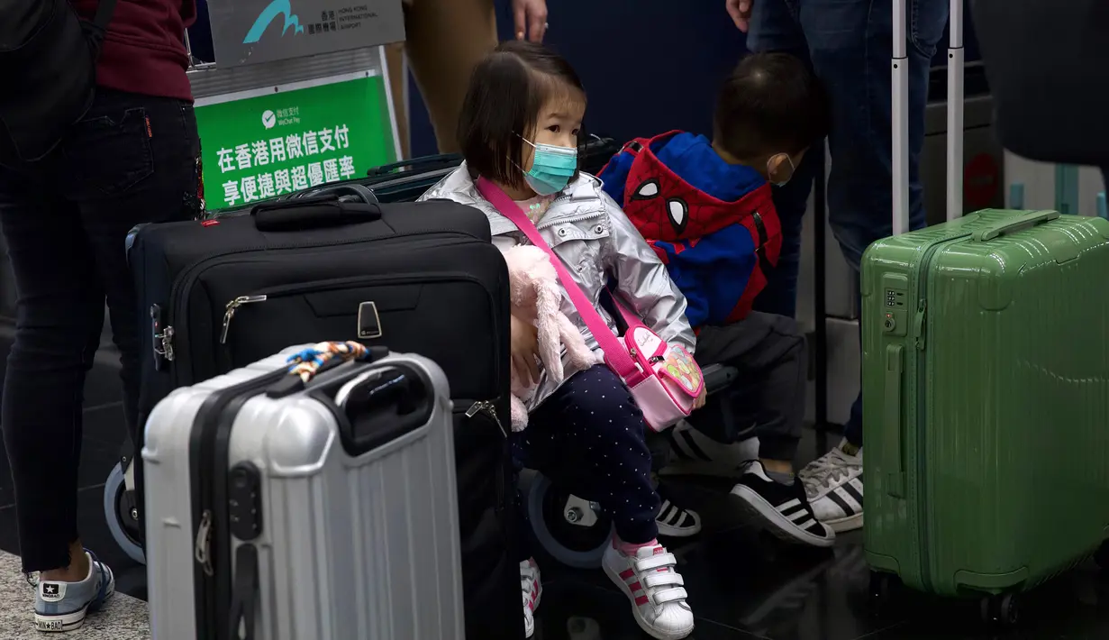 Seorang anak mengenakan masker duduk di antara koper-koper di Bandara Internasional Hong Kong di Hong Kong, Selasa (21/1/2020). Masker terjual habis dan pemeriksaan suhu di bandara dan stasiun kereta api menjadi norma baru di China menyusul merebaknya wabah virus corona.  (AP/Ng Han Guan)