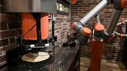 Robot pembuat pizza Bernama "Pazzi" terlihat sedang bekerja di sebuah restoran di Paris pada 1 Juli 2021. Pazzi dapat menjadi cikal bakal pasukan robot koki masa depan di seluruh dunia. (BERTRAND GUAY/AFP)