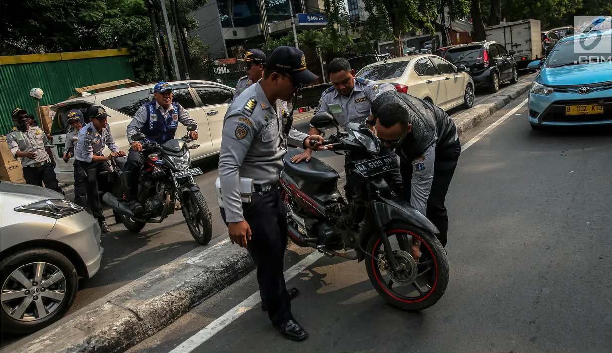 Petugas Dishub mengangkut sepeda motor saat melakukan penertiban parkir liar di atas trotoar kawasan KH Wahid Hasyim, Jakarta, Selasa (1/8). Penertiban dalam rangka Bulan Patuh Trotoar itu untuk mengembalikan fungsi trotoar. (Liputan6.com/Faizal Fanani)