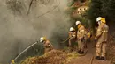 Petugas pemadam mencoba memadamkan api yang membakar hutan dekat rumah di Sao Joao Latrao, Pulau Madeira, Portugal, Rabu (10/8). Sedikitnya 80 orang dirawat di rumah sakit karena luka bakar dan terlalu banyak menghirup asap kebakaran. (REUTERS/Duarte Sa)