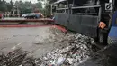 Seorang petugas membersihkan sampah yang menyangkut di Pintu Air Manggarai, Jakarta, Senin (5/2). Volume sampah terus meningkat lebih dari 200 ton. (Liputan6.com/Faizal Fanani)