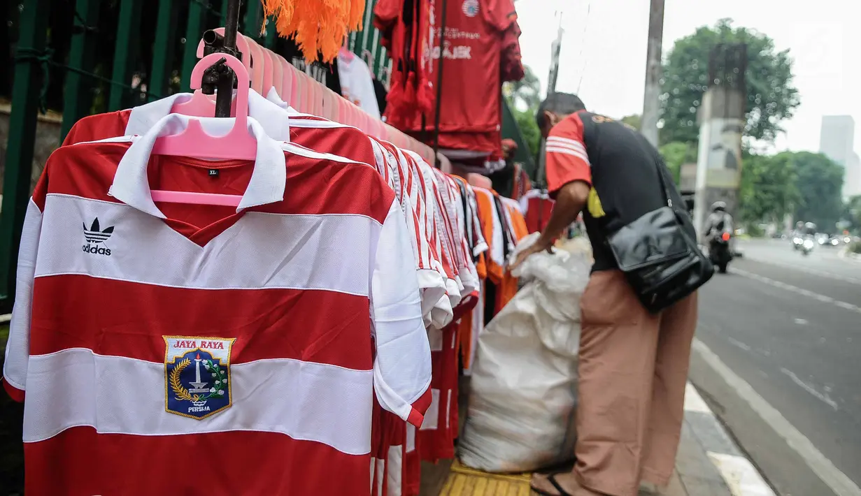 Pedagang merapikan atribut Persija di kawasan Senayan, Jakarta, Minggu (9/12). Pedagang memanfaatkan momen pertandingan Persija Jakarta yang akan bertanding melawan Mitra Kukar. (Liputan6.com/Faizal Fanani)