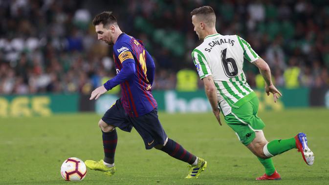 Striker Barcelona, Lionel Messi, berusaha melewati pemain Real Betis, Canales, pada laga La Liga 2019 di Stadion Benito Villamarin, Minggu (17/3). Barcelona menang 4-1 atas Real Betis. (AP/Miguel Morenatti)