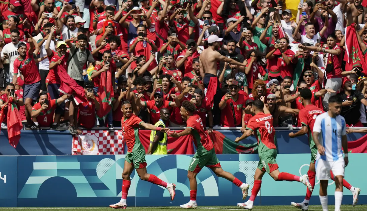 Para pemain Maroko merayakan gol yang dicetak oleh Soufiane Rahimi ke gawang Argentina pada laga pertama grup B Olimpiade 2024 di stadion Geoffroy-Guichard, Rabu (24/7/2024). Argentina tumbang dengan skor 1-2. (AP Photo/Silvia Izquierdo)