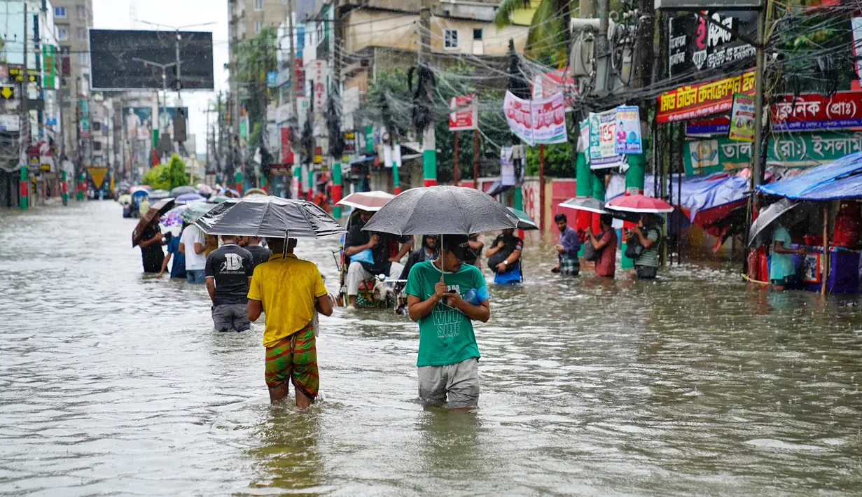 Orang-orang membawa payung menyeberangi jalan yang tergenang air di tengah curah hujan di Feni, Bangladesh pada Kamis 22 Agustus 2024. (Foto oleh AFP)