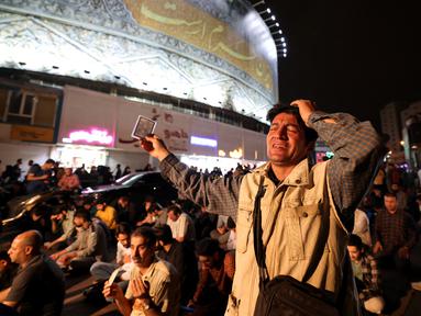 Warga berdoa untuk keselamatan Presiden Iran Ebrahim Raisi dan Menteri Luar Negeri Hossein Amir-Abdollahian di Lapangan Valiasr, pusat Teheran. Minggu (19/5/2024). (ATTA KENARE / AFP)