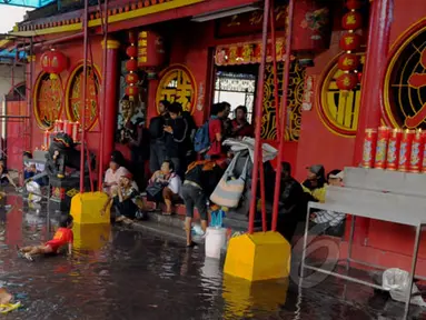 Masyarakat Tionghoa melintasi genangan air di Vihara Dharma Bakti, Petak Sembilan, Jakarta, Kamis (19/2/2015). Hujan deras yang mengguyur kawasan tersebut sekitar pukul 11.30 WIB membuat halaman depan vihara tergenang. (Liputan6.com/Andrian M Tunay)