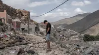 Seorang pemuda berdiri di atas reruntuhan rumah yang hancur di tengah operasi penyelamatan yang sedang berlangsung di desa Imi N'Tala, dekat Amizmiz, pada tanggal 12 September 2023. (BULENT KILIC/AFP)