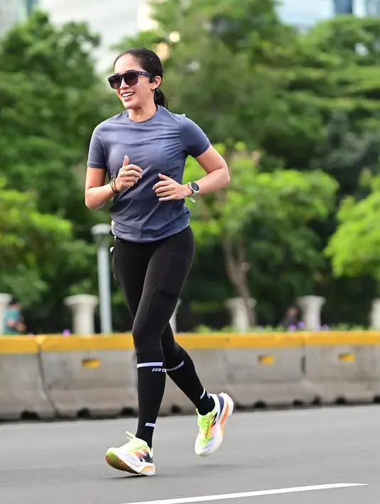 Ia mengenakan dry-fit shirt dengan legging hitam dan sneakers lari bernuansa neon. Lengkap dengan kacamata hitam dan smartwatch di pergelangan tangan. [@ussypratama]