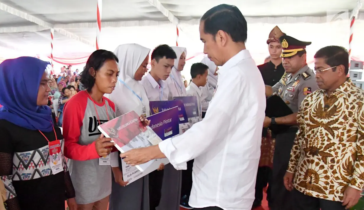Presiden Jokowi menyerahkan kartu Program Keluarga Harapan (PKH) secara simbolis kepada perwakilan warga di SMA Negeri 1 Palembang, Sumatra Selatan (22/1). (Liputan6.com/Pool/Biro Setpres)