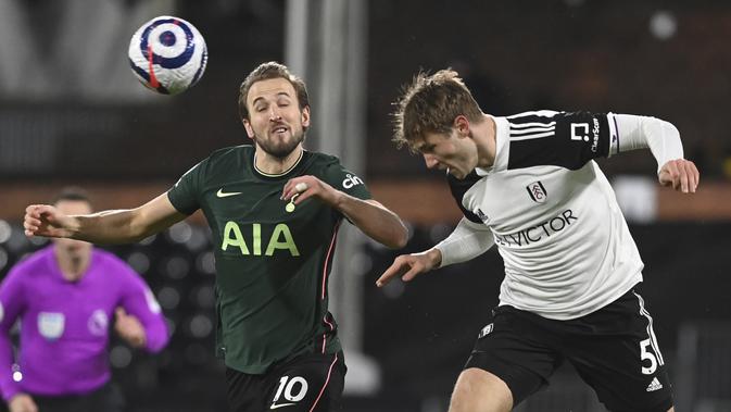 Penyerang Tottenham Hotspur, Harry Kane dan bek Fullham, Joachim Andersen berebut bola pada pekan ke-27 Liga Inggris di Craven Cottage, Jumat (5/3/2021) dini hari WIB. Tottenham Hotspur unggul 1-0 atas Fullham lewat gol bunuh diri Tosin Adarabioyo. (Neil Hall/Pool via AP)