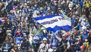 Seorang Bobotoh mengibarkan bendera bertuliskan Bandung Fans di tengah kerumunan pawai usai Persib Bandung menjuarai Liga 1 musim 2023/2024 di Jalan Djunjunan, Sukamulya, Kota Bandung pada Sabtu, 1 Juni 2024. (Liputan6.com/Dikdik Ripaldi)