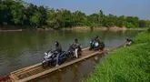 Warga bersama sepeda motornya menyeberangi Sungai Cisadane menggunakan rakit bambu di kawasan Ciseeng, Kabupaten Bogor, Jawa Barat, Kamis (11/6/2026). (merdeka.com/Arie Basuki)