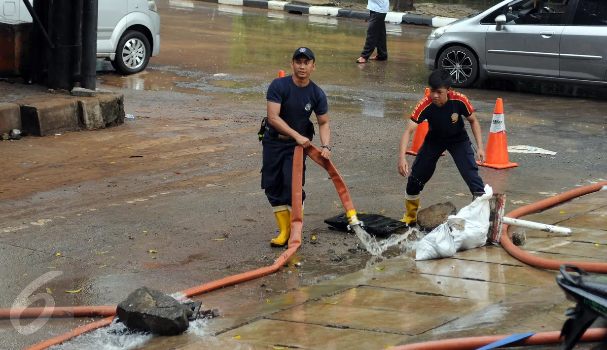Petugas Damkar PB menarik selang pembuangan saat melakukan pengeringan di salah satu pertokoan di Jalan Kemang Raya, Jakarta, Minggu (28/8). Dua lokasi parkir bawah tanah pertokoan di kawasan Kemang terendam air. (Liputan6.com/Helmi Fithriansyah)