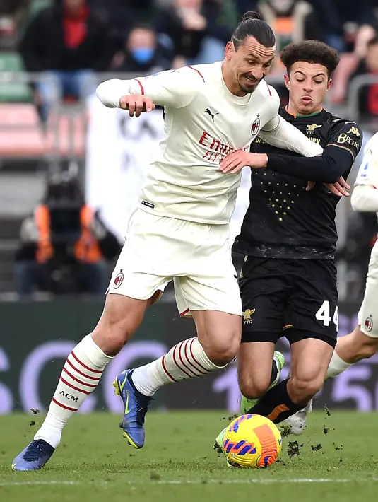 Penyerang AC Milan, Zlatan Ibrahimovic membawa bola dari kawalan bek Venezia, Ethan Ampadu pada pertandingan Liga Serie A Italia di stadion Penzo, Italia, Minggu (9/1/2022). AC Milan kini memporoleh 48 angka dari 21 laga, memimpin dua nilai dari juara bertahan Inter Milan. (AFP/Marco Bertorello)