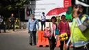 Dua karyawati menggunakan payung sambil berjalan menuju kantornya di sekitar kawasan Bundaran HI, Jakarta, Rabu (22/4/2015). Sejumlah ruas jalan di Jakarta ditutup sementara waktu terkait puncak Konferensi Asia-Afrika (KAA). (Liputan6.com/Faizal Fanani)