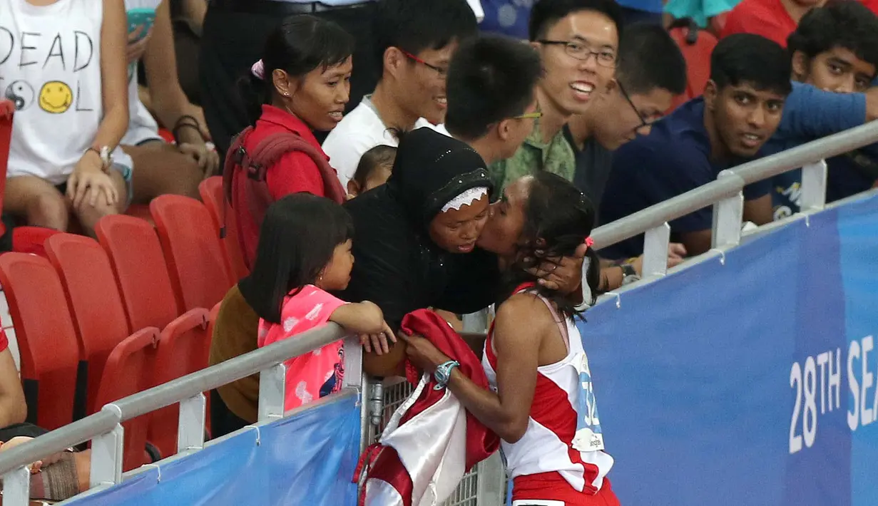 Triyaningsih mendapat pelukan dari sang bunda setelah meraih emas nomor lari 5.000m SEA Games yang berlangsung di Stadion Nasional Singapura. Selasa (9/6). (Bola.com/Arief Bagus)