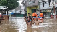 Warga melintasi banjir di perumahan Ciledug Indah, Tangerang, Rabu (1/1/2020). Banjir setinggi dada orang dewasa terjadi akibat meluapnya kali angke. (Liputan6.com/Angga Yuniar)