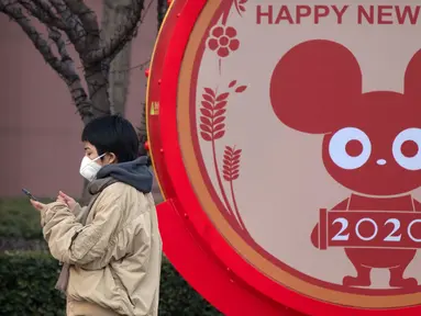 Seorang perempuan mengenakan masker berdiri dekat layar untuk perayaan Imlek Tahun Tikus Logam di Beijing, 22 Januari 2020. Otoritas kesehatan China mendesak orang-orang menghindari keramaian dan pertemuan publik di Wuhan, kota yang menjadi pusat penyebaran wabah virus corona. (AP/Mark Schiefelbein)