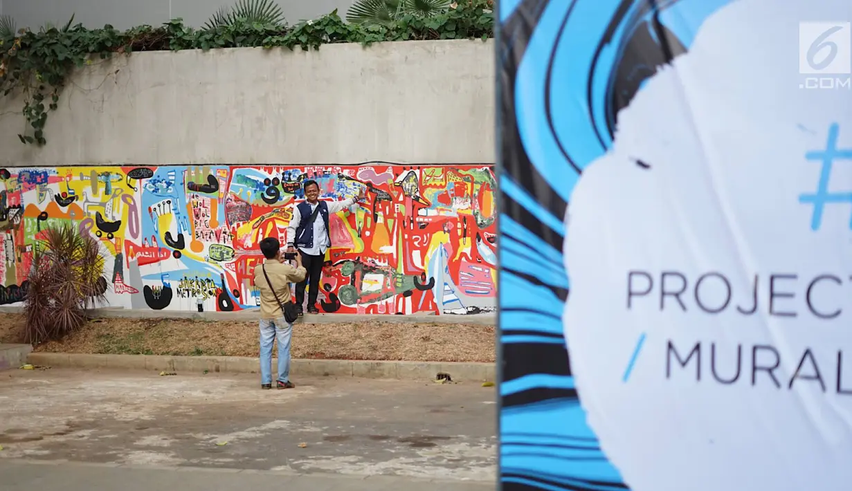 Warga melihat mural yang menghiasi tembok dalam acara Mural Cikini Project #1 di Taman Plaza Teater Besar, Taman Ismail Marzuki, Jakarta, Jumat (23/8/2019). Project #1/Mural Cikini yang diikuti oleh 4 seniman digelar dalam rangka menata estetika ruang publik. (Liputan6.com/Faizal Fanani)