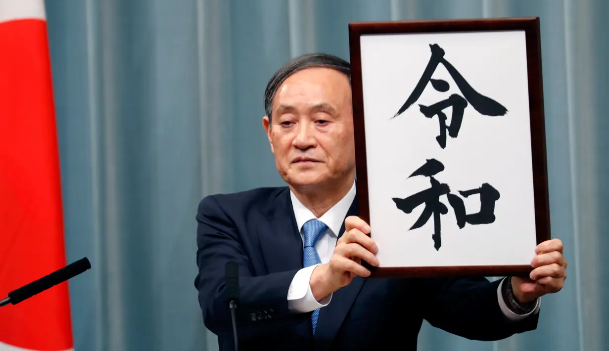 Sekretaris Kabinet Jepang, Yoshihide Suga menunjukkan plakat nama era baru Kekaisaran Jepang, Reiwa, di Tokyo, Senin (1/4). Reiwa, menjadi nama era yang baru yang mengganti Era Heisei seiring persiapan pengunduran diri Kaisar Akihito pada 31 April mendatang. (AP/Eugene Hoshiko)