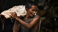 Gambar pada 9 Februari 2020 menunjukkan pekerja membawa potongan pohon sagu untuk diolah menjadi tepung di sebuah desa di Meulaboh, provinsi Aceh. Berwarna putih agak pucat, tepung ini sering digunakan untuk pembuatan berbagai makanan dan masakan. (CHAIDEER MAHYUDDIN/AFP)