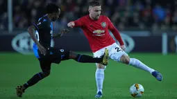 Bek Manchester United, Luke Shaw, berebut bola dengan pemain Club Brugge, Percy Tau dalam leg pertama babak 32 besar Liga Europa di Jan Breydelstadion, Kamis (20/2/2020). Manchester United gagal meraih hasil maksimal usai ditahan imbang Club Brugge 1-1. (AP/Francisco Seco)