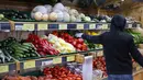 Seorang pemilik kios mengisi kembali paprika di pajangan sayuran di luar sebuah toko di Walthamstow, London, Minggu (22/11/2021). Indeks Harga Konsumen Inggris naik ke angka 4,2 persen dalam 12 bulan hingga Oktober 2021, mencapai level tertinggi sejak November 2011. (Tolga Akmen/AFP)
