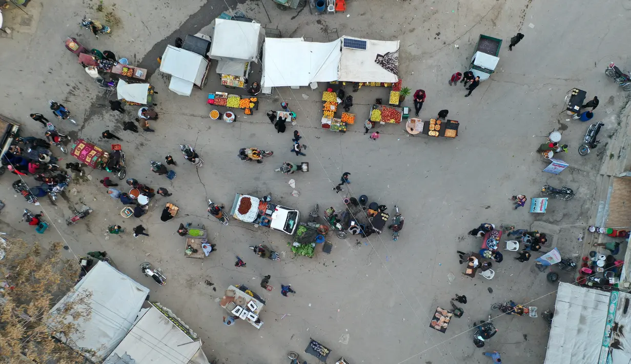 Pemandangan udara saat warga Suriah membeli produk makanan di pasar menjelang buka puasa pada hari kedua Ramadhan, di kota Ariha yang dilanda perang, di provinsi Idlib, Kamis (15/4/2021). Mereka menjalankan Ramadhan di antara lautan reruntuhan bekas konflik gencatan senjata. (Omar HAJ KADOUR/AFP)