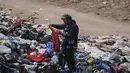 Alexis Carreno melihat-lihat tumpukan besar pakaian bekas yang menutupi gurun pasir di dekat lingkungan La Mula di Alto Hospicio, Chile, Senin (13/12/2021). Chile adalah importir besar pakaian bekas, dan barang-barang yang tidak terjual dibuang di sini. (AP Photo/Matias Delacroix)
