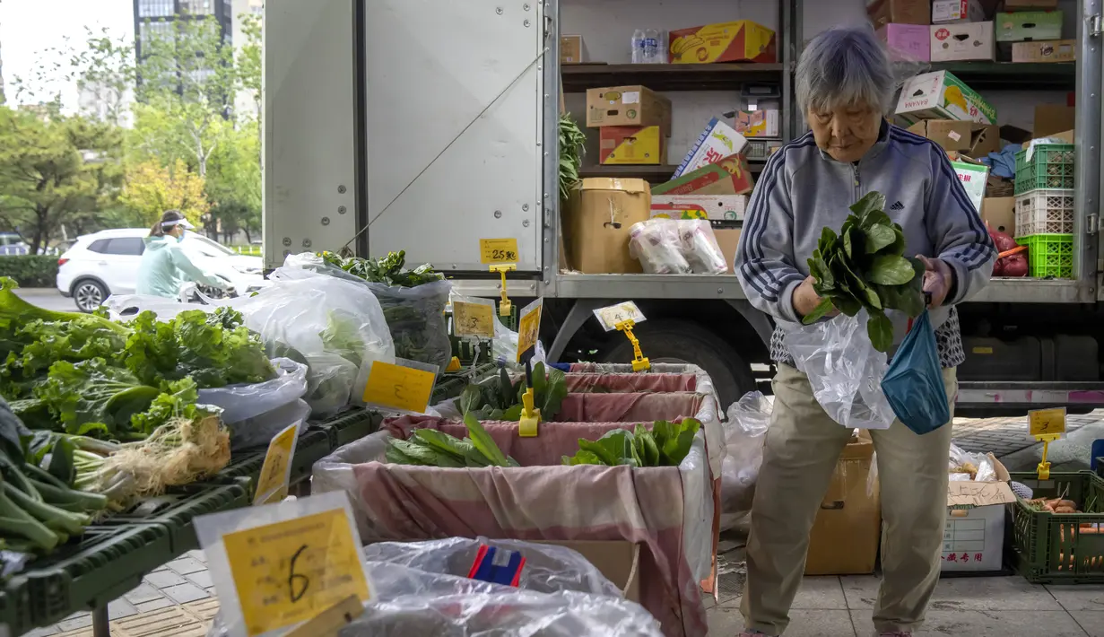 <p>Seorang wanita berbelanja sayuran segar di pasar pop-up di Beijing, Kamis (28/4/2022). Beijing mengalihkan lebih banyak kelas secara online pada hari Kamis dalam pengetatan pembatasan COVID-19 lebih lanjut, karena ibu kota China berupaya mencegah penyebaran yang lebih luas. (AP Photo/Mark Schiefelbein)</p>