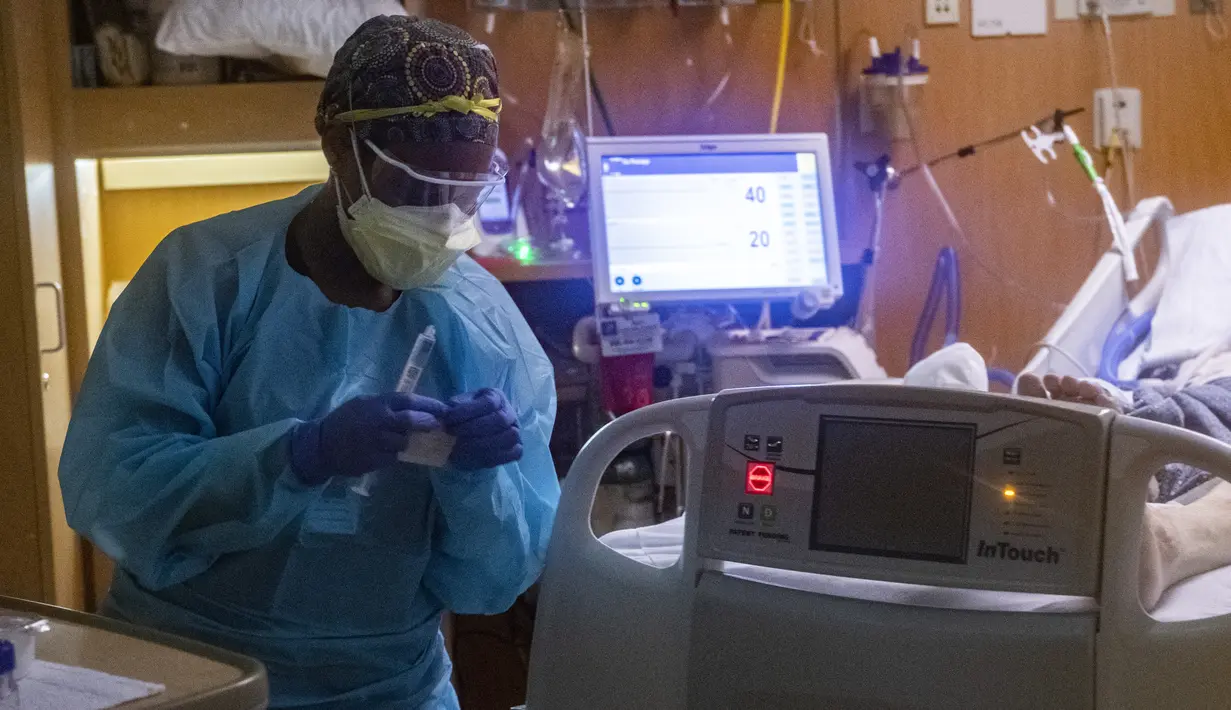 Pekerja medis merawat pasien covid-19 di ruang tekanan negatif di bangsal ICU UMass Memorial Medical Center di Worcester, Massachusetts, Selasa (4/1/2022). Menurut data, Massachusetts saat ini memiliki 2.221 rawat inap pasien covid dengan 402 di kamar ICU dan 245 diintubasi. (Joseph Prezioso/AFP)