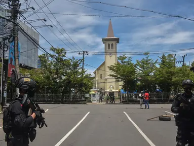 Polisi berjaga di luar gereja setelah ledakan di Makassar (28/3/2021). Ledakan diduga bom terjadi di depan Gereja Katedral Makassar, Sulawesi Selatan pada Minggu (28/3/2021). (AFP/Indra Abriyanto)