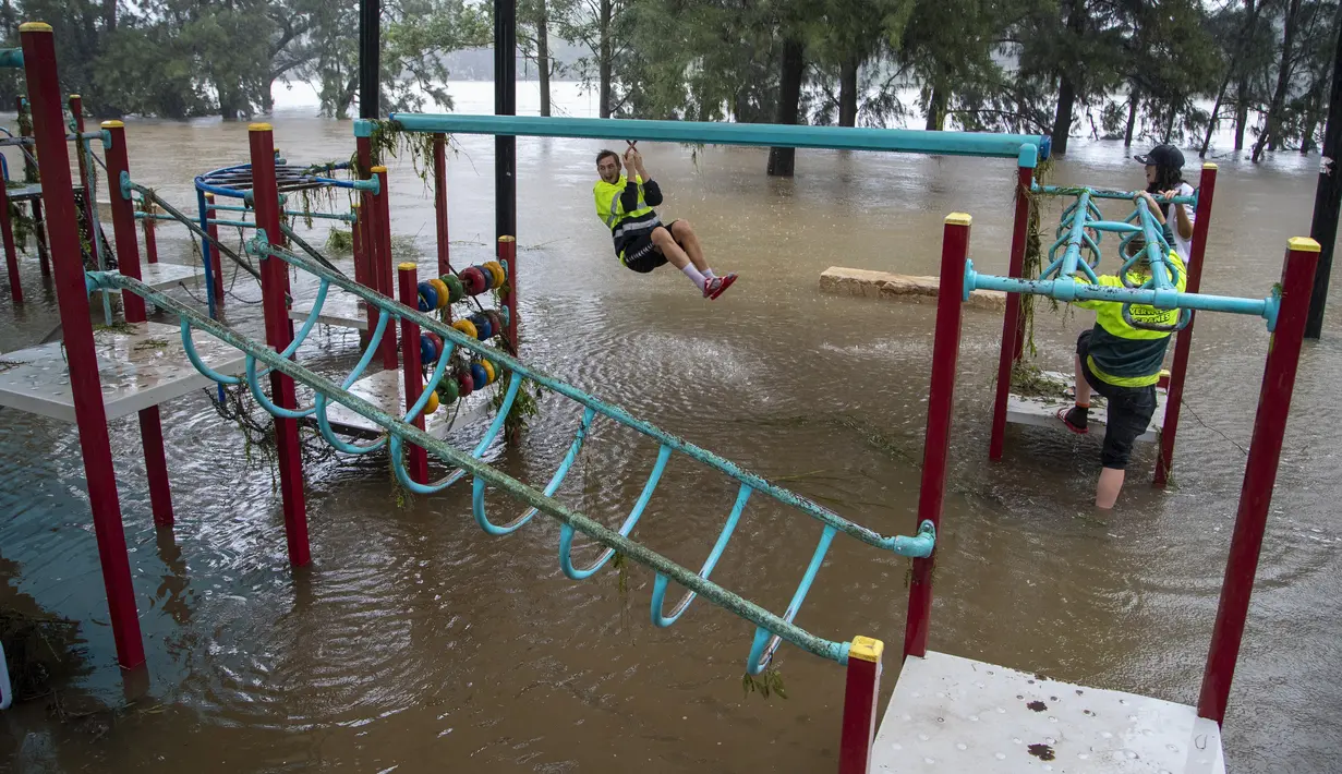 Orang-orang bermain dengan peralatan di taman bermain di tepi Sungai Nepean di Jamisontown di pinggiran barat Sydney (22/3/2021). Banjir membuat  ribuan orang mengungsi dari rumah mereka karena hujan masih melanda wilayah tersebut. (AP Photo/Mark Baker)
