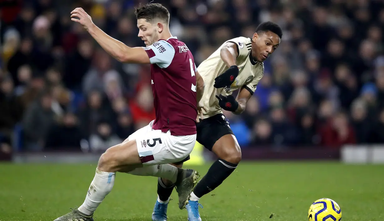 Pemain Manchester United Anthony Martial (kanan) berebut bola dengan pemain Burnley James Tarkowski pada pertandingan Liga Inggris di Turf Moor, Burnley, Inggris, Sabtu (28/12/2019). MU menang 2-0 dan melonjak ke posisi lima klasemen. (Martin Rickett/PA via AP)