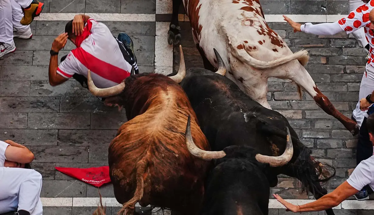 Pengunjung berlari di samping banteng-banteng petarung Victoriano del Río selama acara lari banteng ketiga di festival San Fermín di Pamplona, Spanyol, Kamis, 9 Juli 2026. (AP Photo/Miguel Oses)