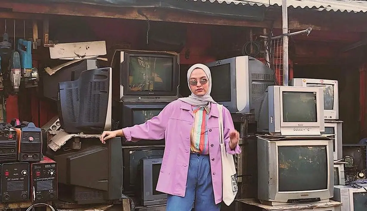 Tampilan hijaber Tasya Kisty ini bisa memberikan kesan vintage. Padukan kemeja stripe warna-warni dengan oversized shirt warna pink. Untuk bawahan, kamu bisa memilih celana jeans panjang dan sneakers. (Instagram/tasyakisty).