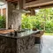 Inspirasi desain dapur bergaya tropis modern kombinasi roster dan batu alam. [Gemini AI]