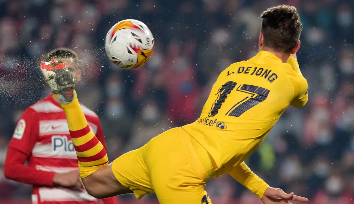 Penyerang Barcelona Luuk de Jong menendang bola saat berebut bola dengan pemain Granada dalam jornada ke-20 Liga Spanyol 2021/2022 di Stadion Los Carmenes, Minggu (9/1/2022) dini hari WIB. Barcelona ditahan imbang 1-1 Granada. (JORGE GUERRERO / AFP)