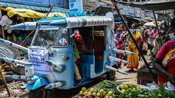 Seorang pekerja kota mengendarai bajaj yang dihiasi dengan jarum suntik tiruan di jalanan di Chennai, India pada Sabtu (3/6/2021). Seorang seniman di Chennai menghias bajaj tersebut untuk meningkatkan kesadaran orang-orang tentang pentingnya vaksinasi Covid-19. (Arun SANKAR/AFP)