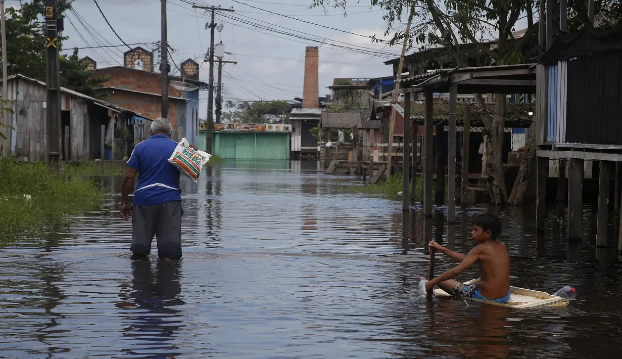 <p>Seorang anak laki-laki menggunakan pintu lemari es untuk mengapung di seberang jalan yang dibanjiri oleh naiknya sungai Negro di Iranduba, negara bagian Amazonas, Brasil, Senin (23/5/2022). Wilayah Amazon sedang dilanda banjir dengan 35 kotamadya yang menghadapi salah satu banjir terburuk mereka dalam beberapa tahun dan permukaan air diperkirakan akan meningkat selama beberapa bulan mendatang. (AP Photo/Edmar Barros)</p>
