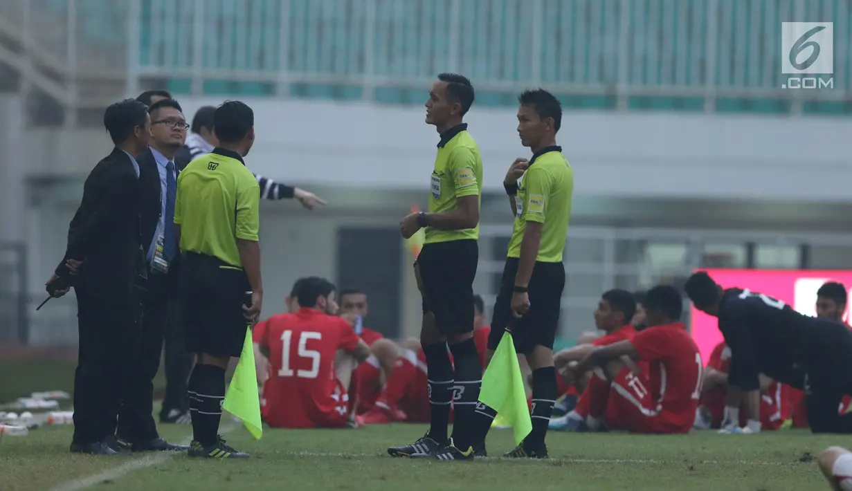 Wasit Mustafa Umarella (kedua kanan) berbincang dengan pengawas pertandingan saat laga Bahrain melawan Korea Utara dihentikan akibat lampu mati pada  PSSI Anniversary Cup 2018 di Stadion Pakansari, Kab Bogor, Kamis (3/5). (Liputan6.com/Helmi Fithriansyah)
