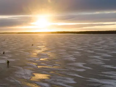 Pandangan udara menunjukkan para pria  sedang memancing di tengah Laut Bothnia yang membeku di dekat Vaasa, Finlandia, 28 Desember 2018. Memancing di laut beku merupakan hal yang ditunggu-tunggu oleh sebagian warga setempat. (OLIVIER MORIN / AFP)