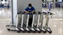 Seorang petugas berdiri di dekat troli bagasi di Bandara Suvarnabhumi di Bangkok, saat Thailand melanjutkan skema perjalanan bebas karantina untuk pelancong yang divaksinasi, Selasa (1/2/2022). Program ini sebelumnya ditangguhkan karena melonjaknya kasus Covid-19 di Thailand. (Jack TAYLOR/AFP)