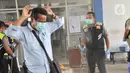Petugas Direktorat Lalu Lintas Polda Jawa Tengah menyemprotkan disinfektan ke calon penumpang saat sterilisasi puluhan angkutan bus yang masuk di Terminal Bawen, Jumat (27/3/2020). (Liputan6.com/Gholib)