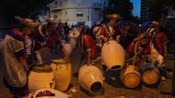Penabuh genderang menyetel drum mereka dengan memanaskan kulit di atas api unggun selama parade karnaval "Las llamadas" di Montevideo, Uruguay, Kamis (10/2/2022). (AP Photo/Matilde Campodonico)